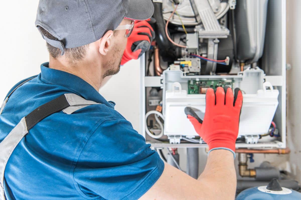 HVAC technician inspecting and servicing a furnace in a home.