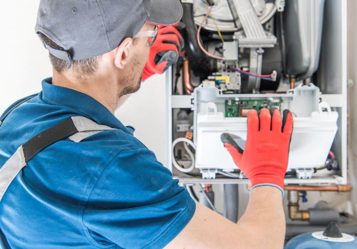 HVAC technician inspecting and servicing a furnace in a home.