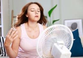 person in front of fan trying to cool off in her humid house